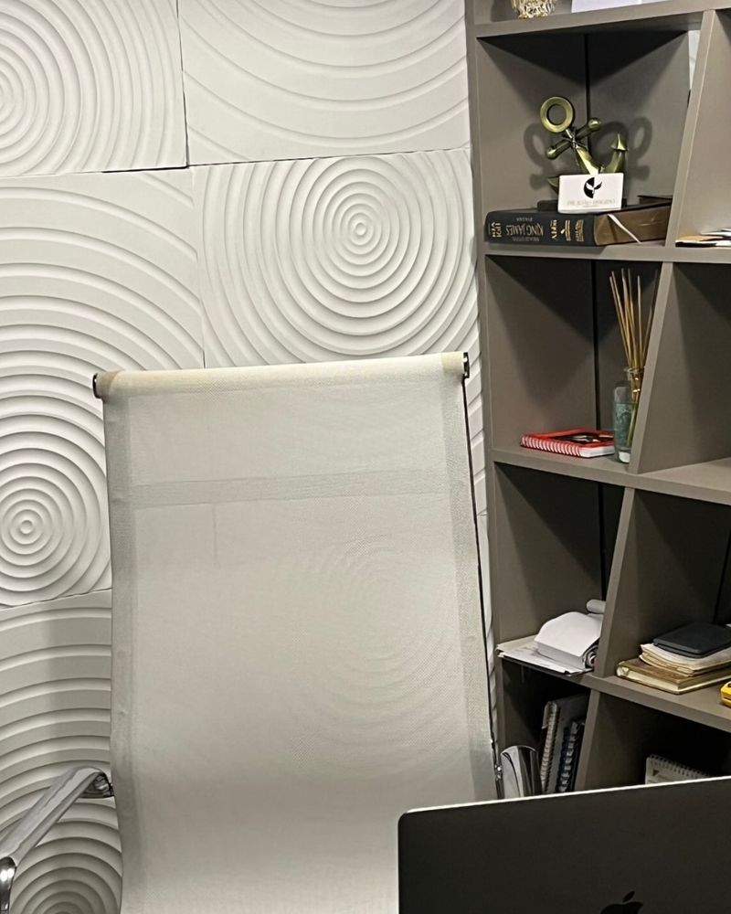 Sala de atendimento, com parede branca em relevo de círculos e estante de livros
